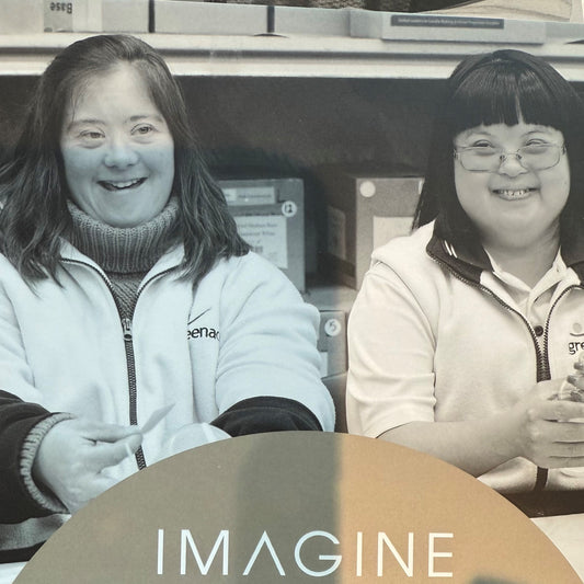Two people sitting together with the word 'IMAGINE' displayed.