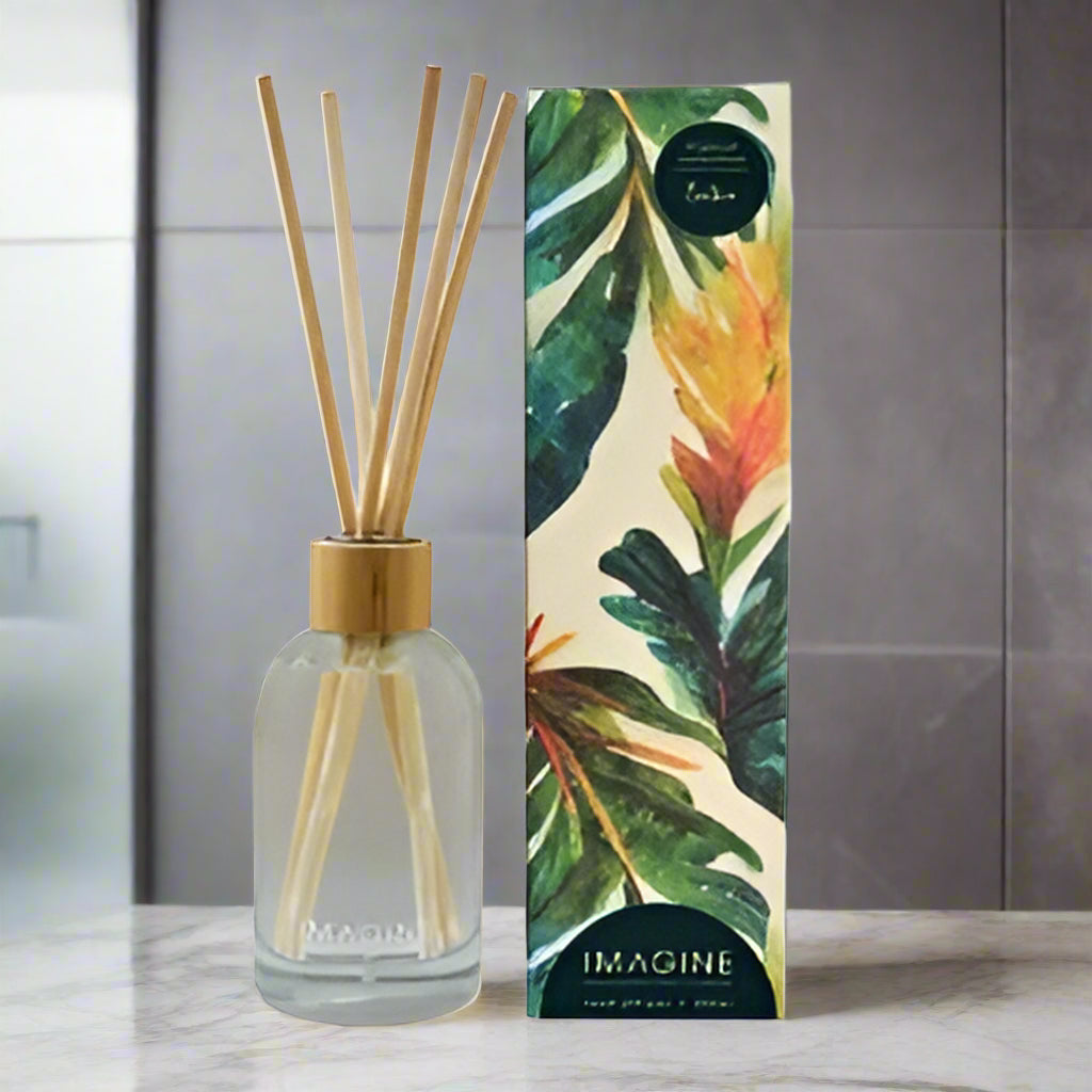 Diffuser bottle with reeds and decorative box featuring tropical leaves on a white background