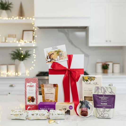 Assorted gift items including a large white box with a red ribbon on a kitchen counter.