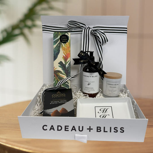 Gift box from Cadeau + Bliss with various items including a candle, truffles, and a bottle of wine.